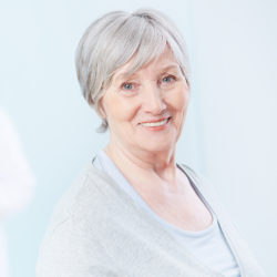 Senior patient looking at camera with doctor on background