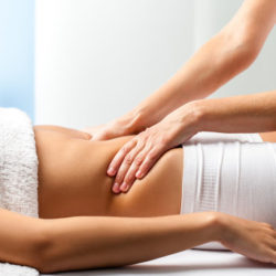 Close up of osteopath doing manipulative abdomen massage on female patient.
