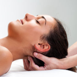 Close up of  chiropractor pressing back of womans head. Therapist doing healing massage with fingers at back of neck.